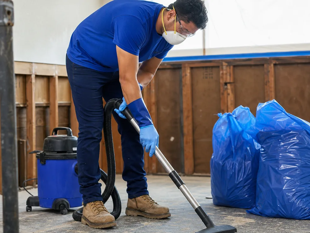 HEPA vacuuming exposed studs and subfloor inside a contained mold remediation area